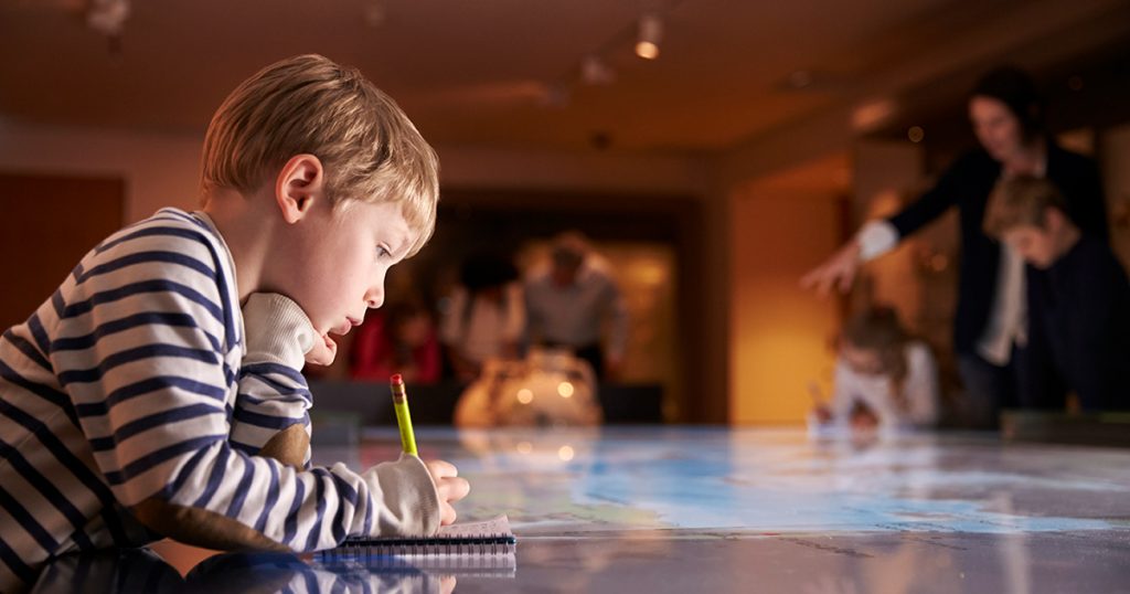Child taking notes at museum display